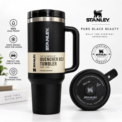 A black Stanley Quencher H2.0 tumbler with a handle, shown alongside its matching black lid on a white background with product feature icons and branding.