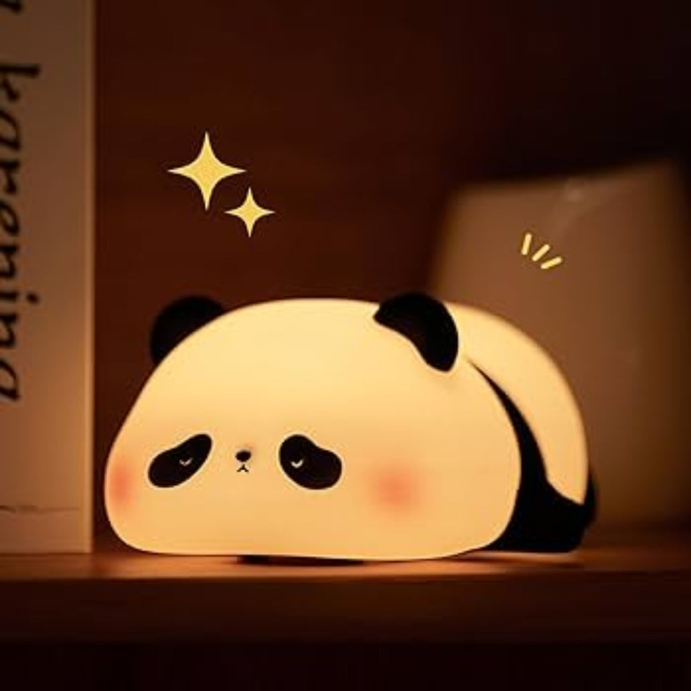 A cute panda-shaped night light glowing warmly on a wooden shelf, with black ears, eyes, and feet, a cream face, and small pink cheeks. Decorative sparkles float above it.