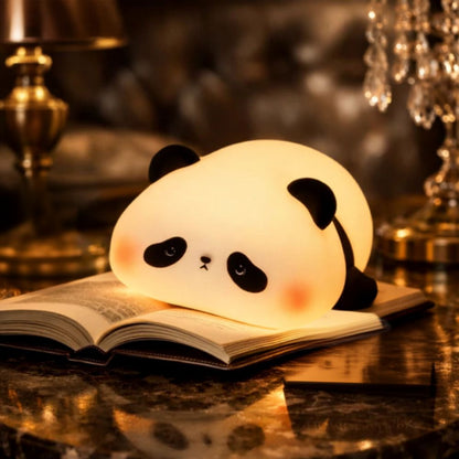 A cute, glowing panda-shaped night light resting on an open book on a polished dark table, with warm ambient background lighting.